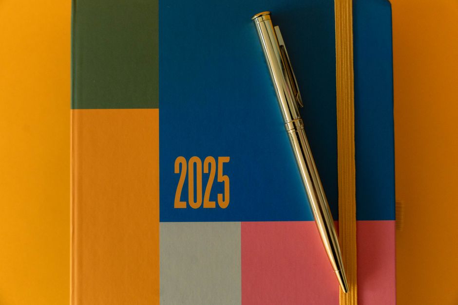 A close-up of a desktop calendar with a pen resting on it, symbolizing the process of planning a realistic timeline to get a real estate license.