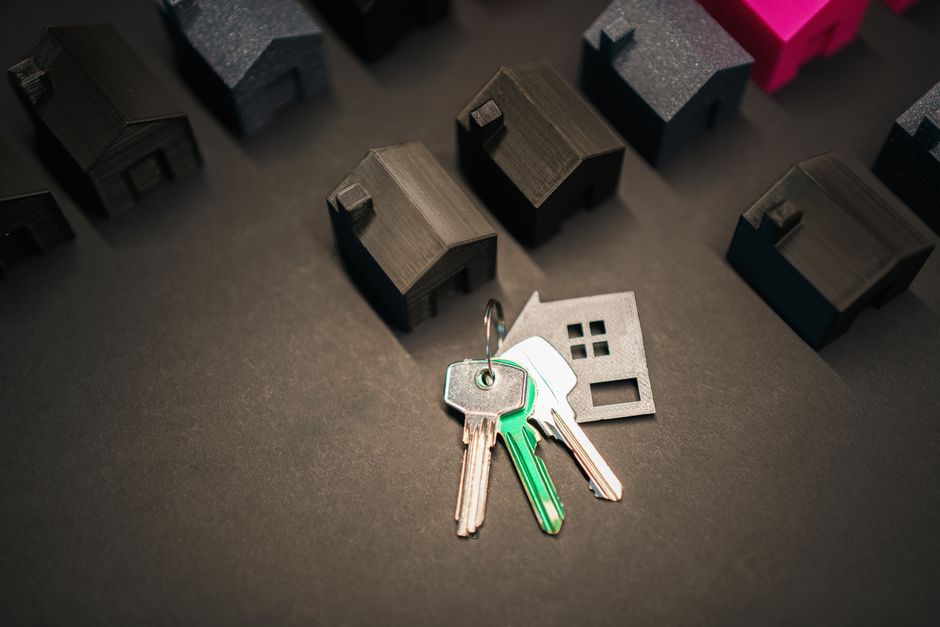 A set of modern house keys rests on a professional desk next to a laptop, symbolizing the rewarding career outcome of completing the real estate licensing process.