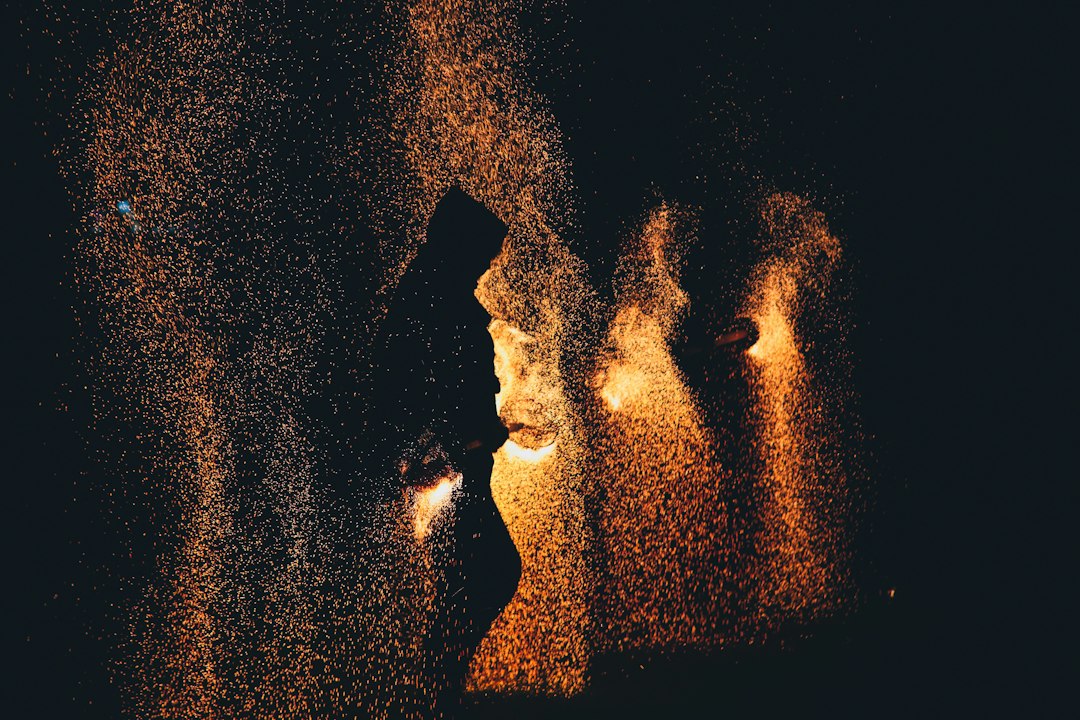 Person's face is shown in a distorted, glitchy reflection on a dark computer screen, symbolizing digital manipulation and ...